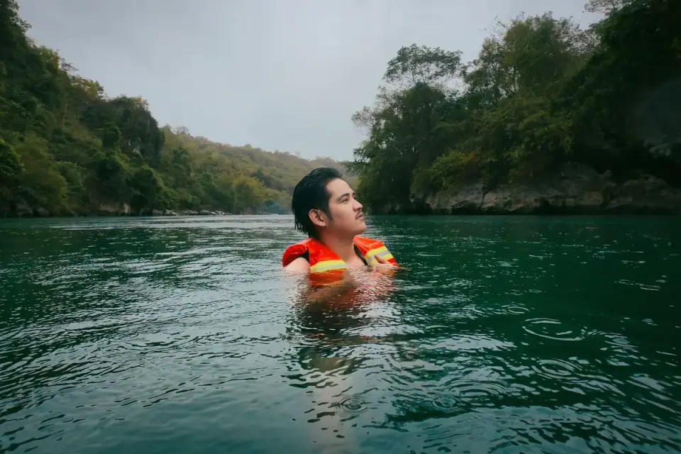 A beagle mix wearing a fitted life jacket while swimming in a lake