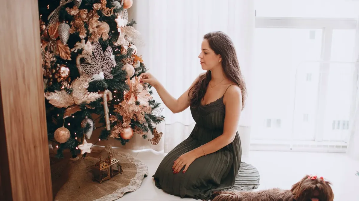 A dog resting calmly on the floor near a decorated Christmas tree