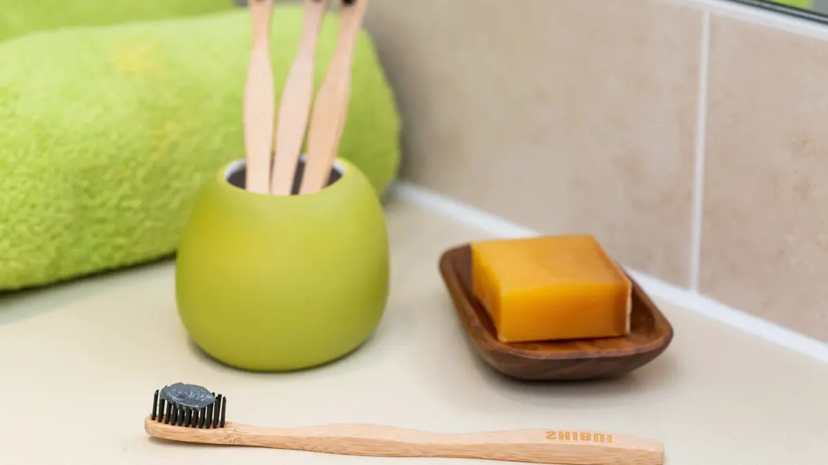A dog-safe toothbrush and toothpaste tube resting on a bathroom counter next to a small dog