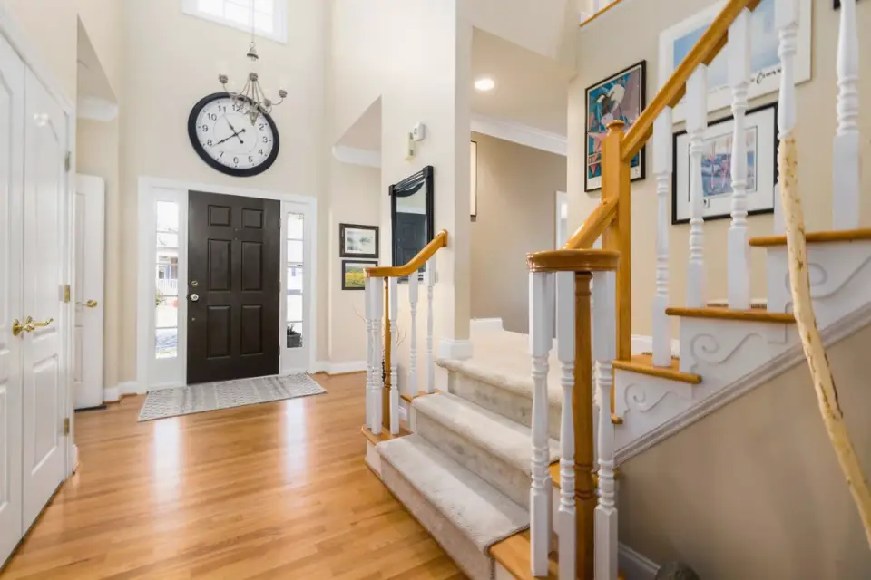 A large senior dog pausing partway up a set of hardwood stairs